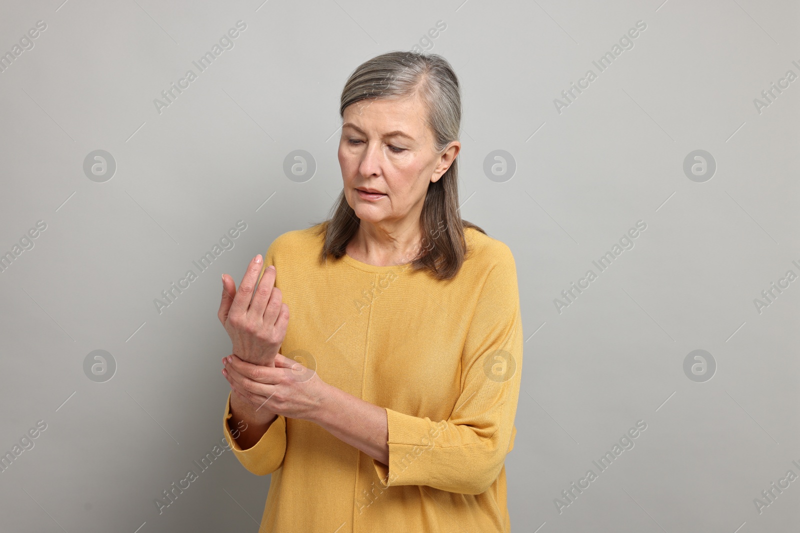 Photo of Arthritis symptoms. Woman suffering from pain in wrist on gray background