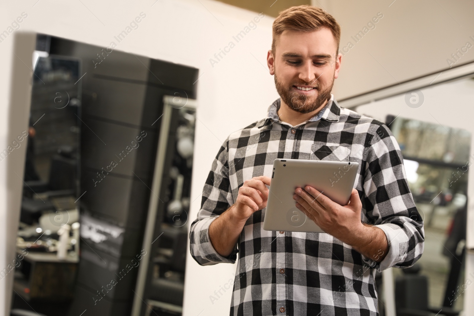 Photo of Young business owner with tablet in barber shop