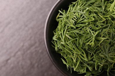 Photo of Fresh cut dill in bowl on dark table, top view. Space for text