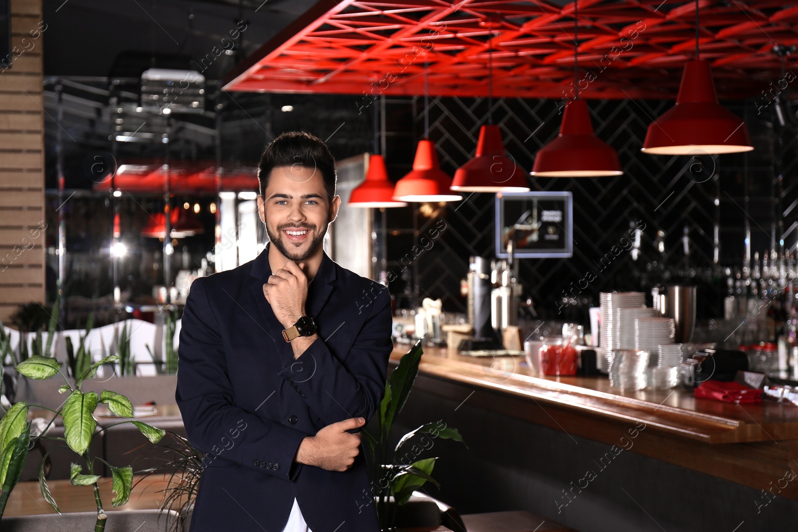 Photo of Young business owner standing in his cafe. Space for text