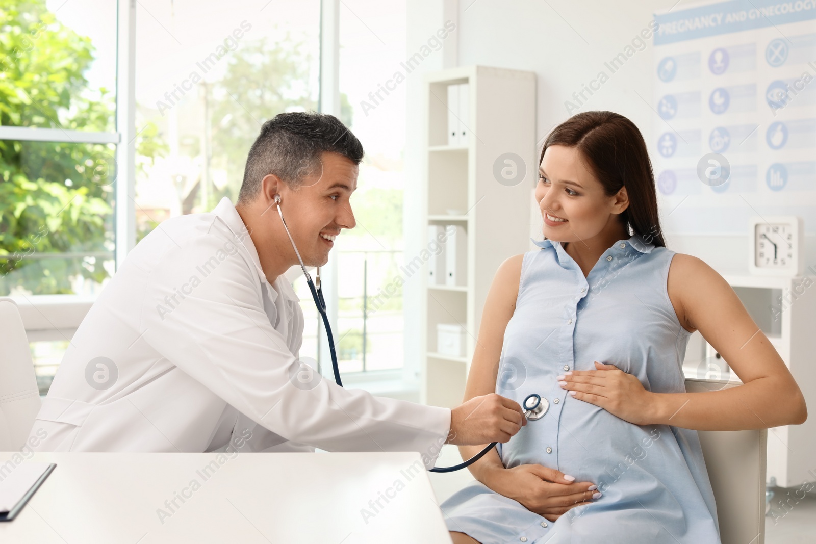 Photo of Young doctor examining pregnant woman in hospital. Patient consultation