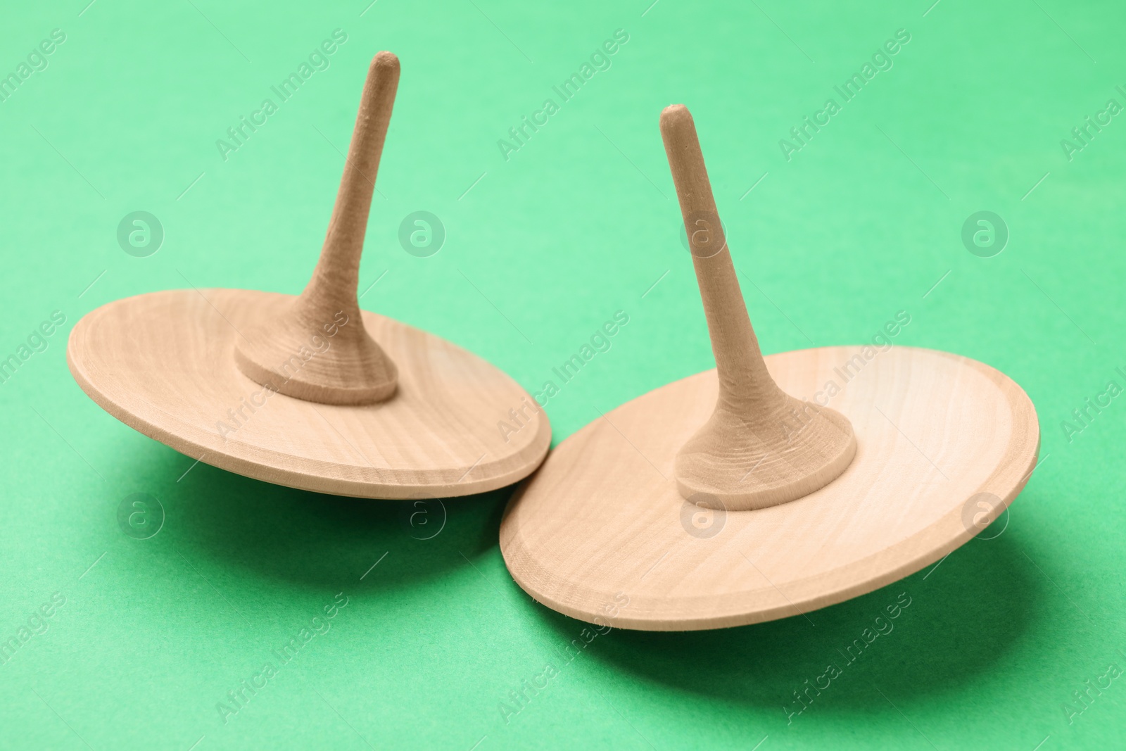 Photo of Two wooden spinning tops on aquamarine background, closeup