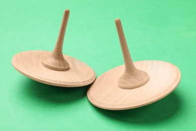 Photo of Two wooden spinning tops on aquamarine background, closeup