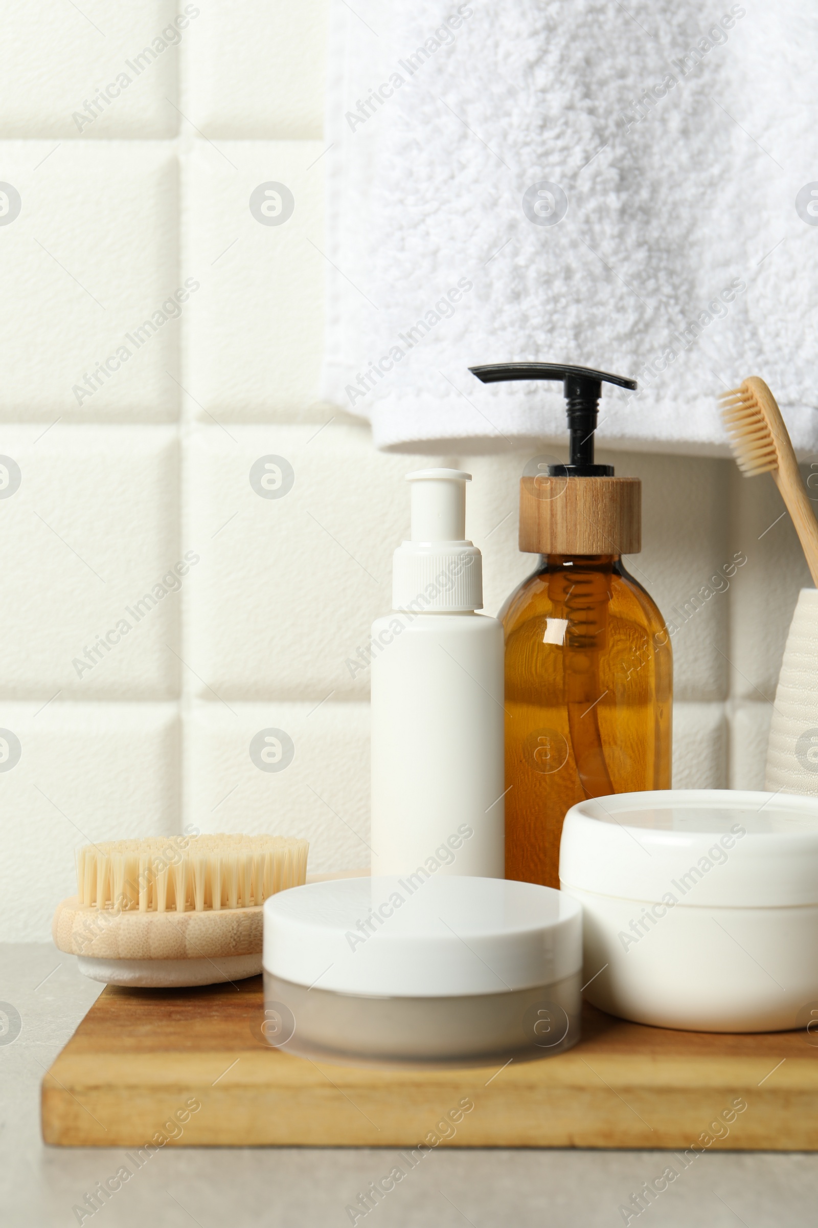 Photo of Different bath accessories and personal care products on gray table near white tiled wall