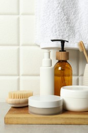 Different bath accessories and personal care products on gray table near white tiled wall