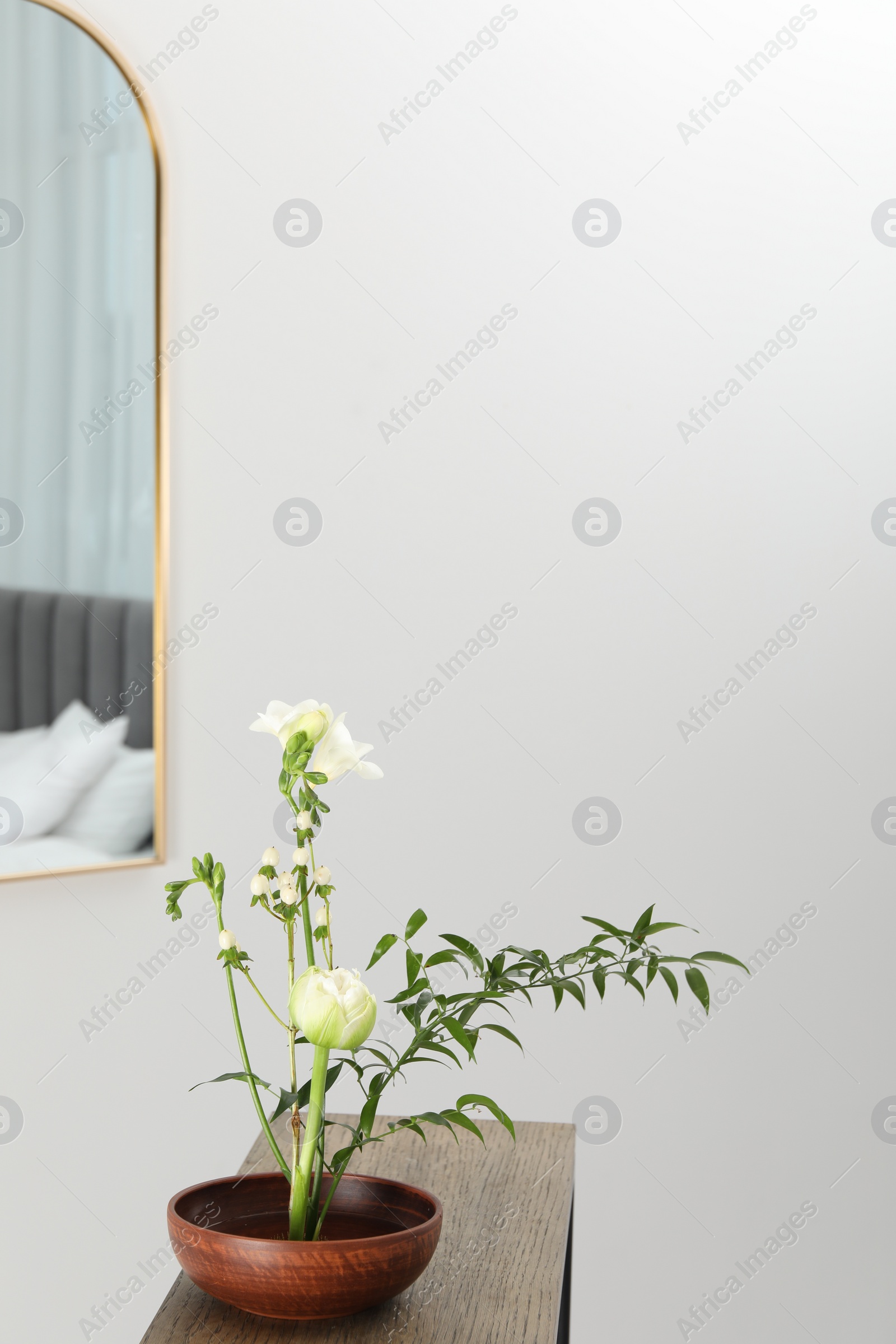 Photo of Stylish ikebana with beautiful flowers and green branch carrying cozy atmosphere at home