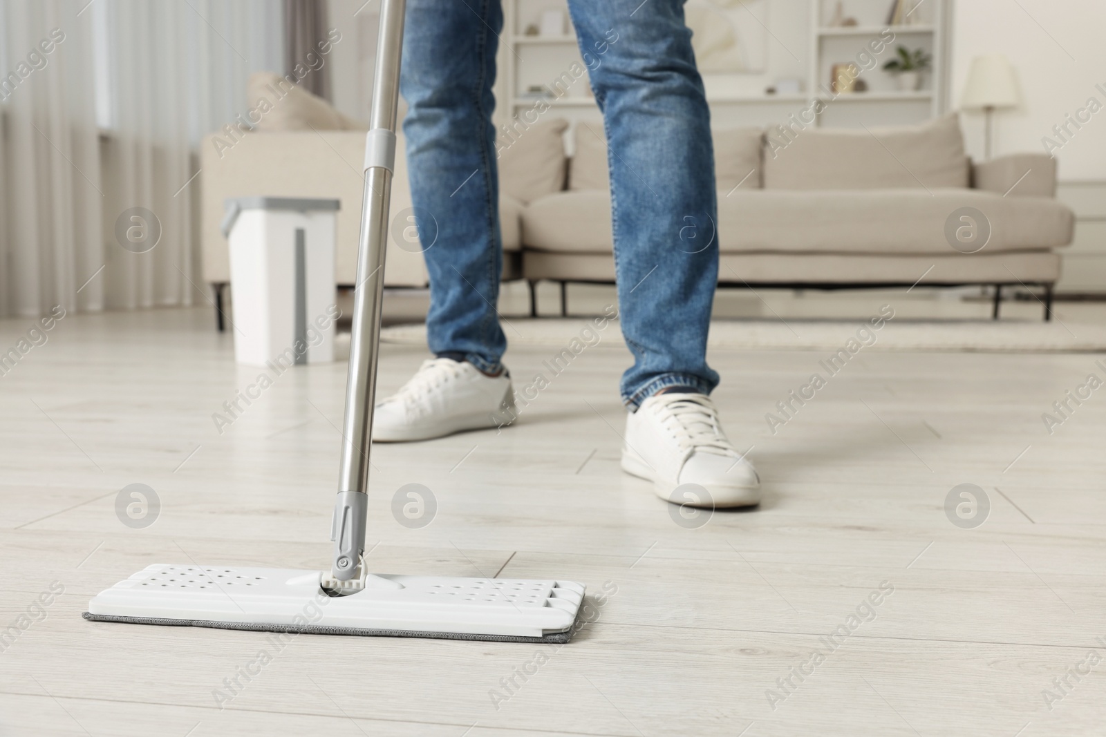 Photo of Man cleaning floor with mop at home, closeup