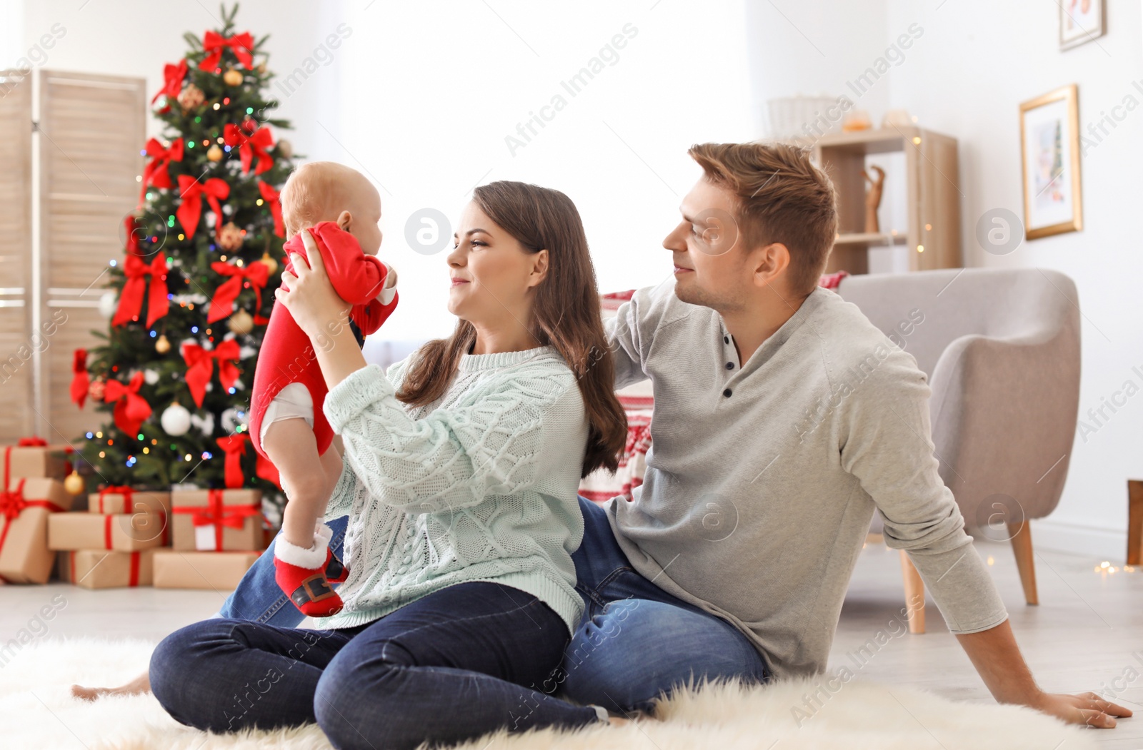 Photo of Happy couple with baby celebrating Christmas together at home