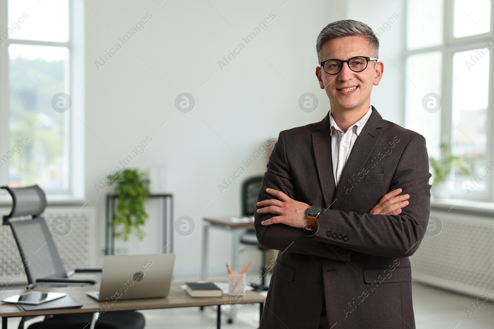 Photo of Happy man with crossed arms in office