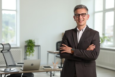 Photo of Happy man with crossed arms in office