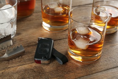 Photo of Glasses of alcohol and car key on wooden table, closeup. Drunk driving concept
