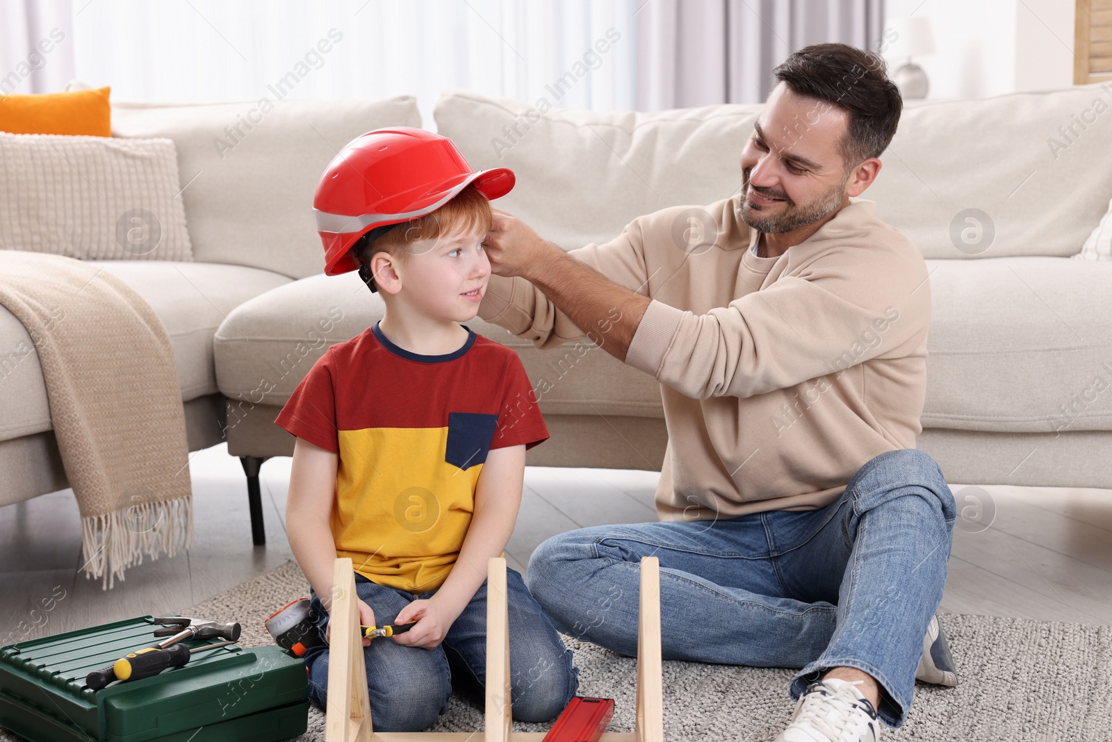 Photo of Father putting hard hat on his son at home. Repair work