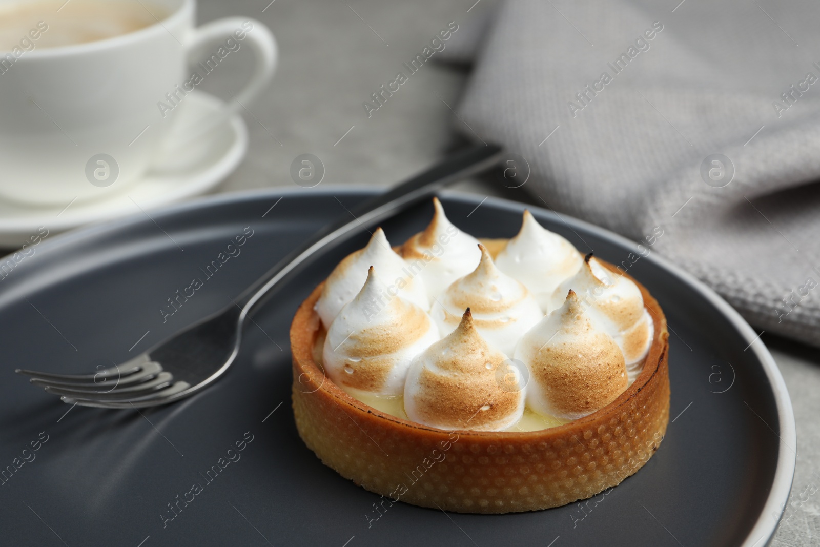 Photo of Tartlet with meringue served on grey table, closeup. Delicious dessert