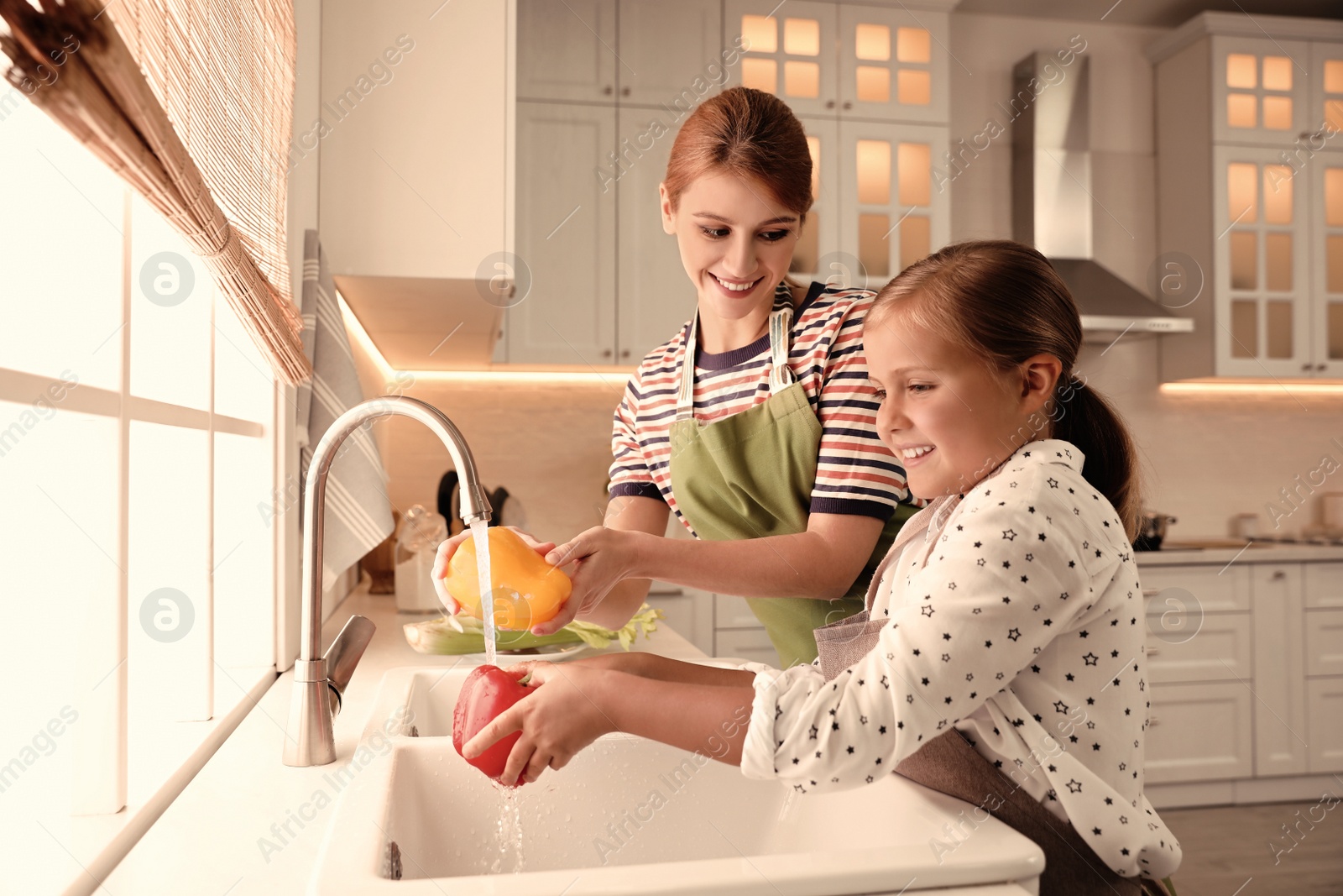 Photo of Mother and daughter washing vegetables in kitchen