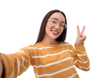 Photo of Smiling young woman taking selfie and showing peace sign on white background