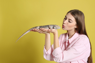 Woman holding bearded lizard on yellow background. Exotic pet