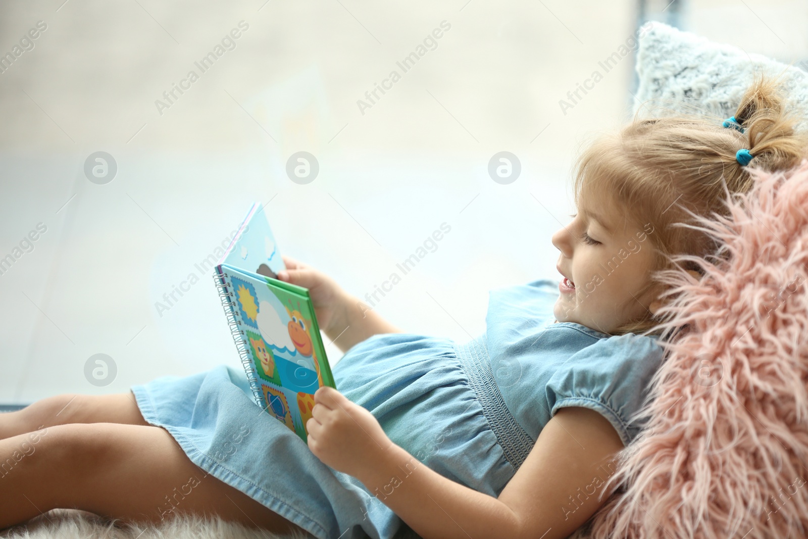 Photo of Cute little girl with book at home