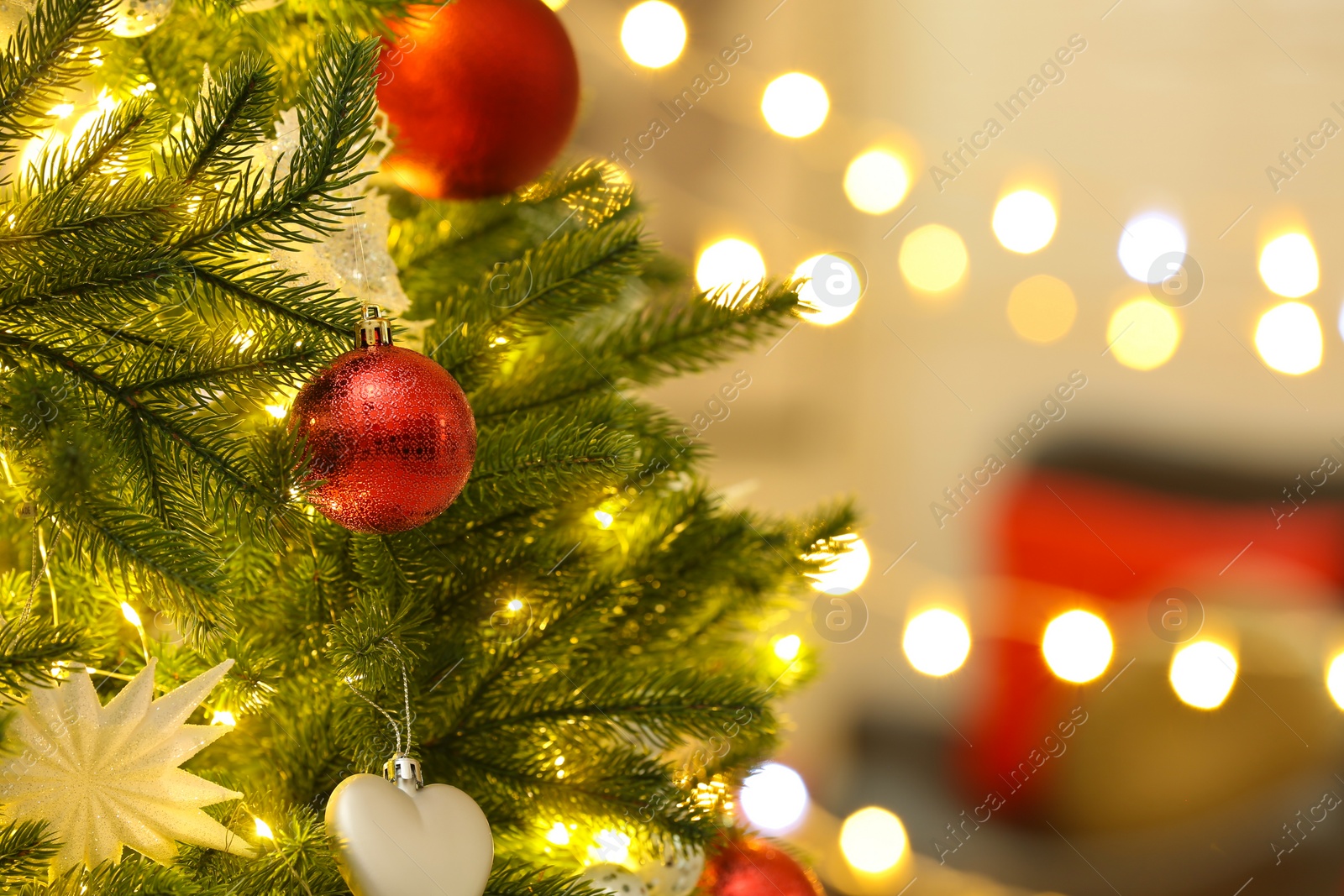 Photo of Color holiday baubles hanging on Christmas tree against blurred lights