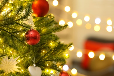 Photo of Color holiday baubles hanging on Christmas tree against blurred lights