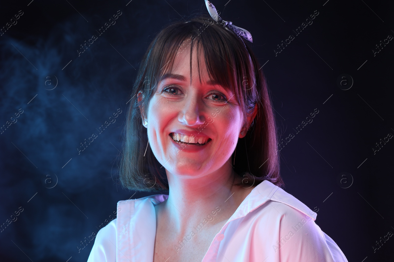 Photo of Portrait of happy woman in smoke on dark background
