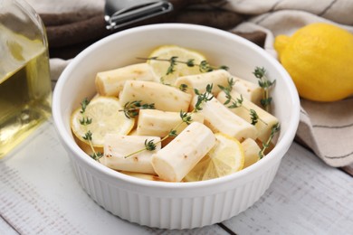 Dish with raw salsify roots, lemon and thyme on white wooden table, closeup