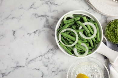 Photo of Flat lay composition with raw green beans on white marble table. Space for text