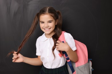 Back to school. Cute girl with backpack near chalkboard