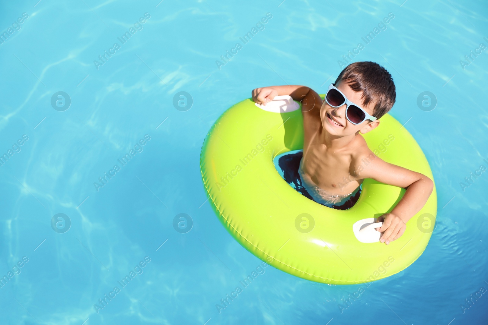 Photo of Little boy with inflatable ring in swimming pool