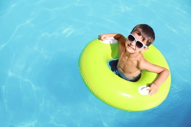Photo of Little boy with inflatable ring in swimming pool