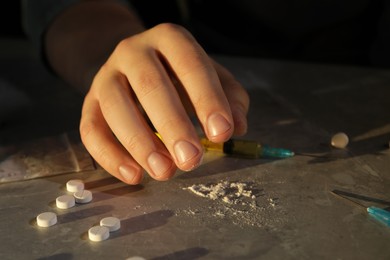 Photo of Addicted man with drugs at grey textured table, closeup