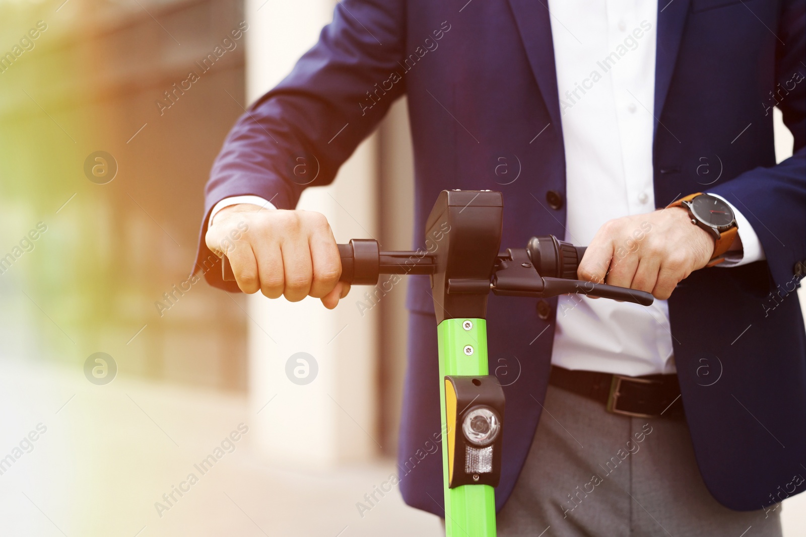 Photo of Businessman with modern kick scooter on city street, closeup