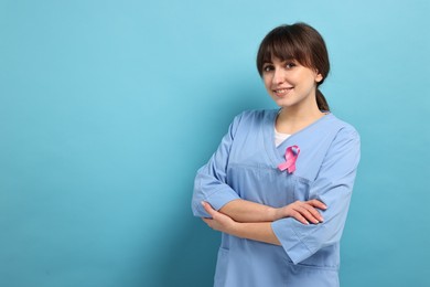Mammologist with pink ribbon on light blue background, space for text. Breast cancer awareness