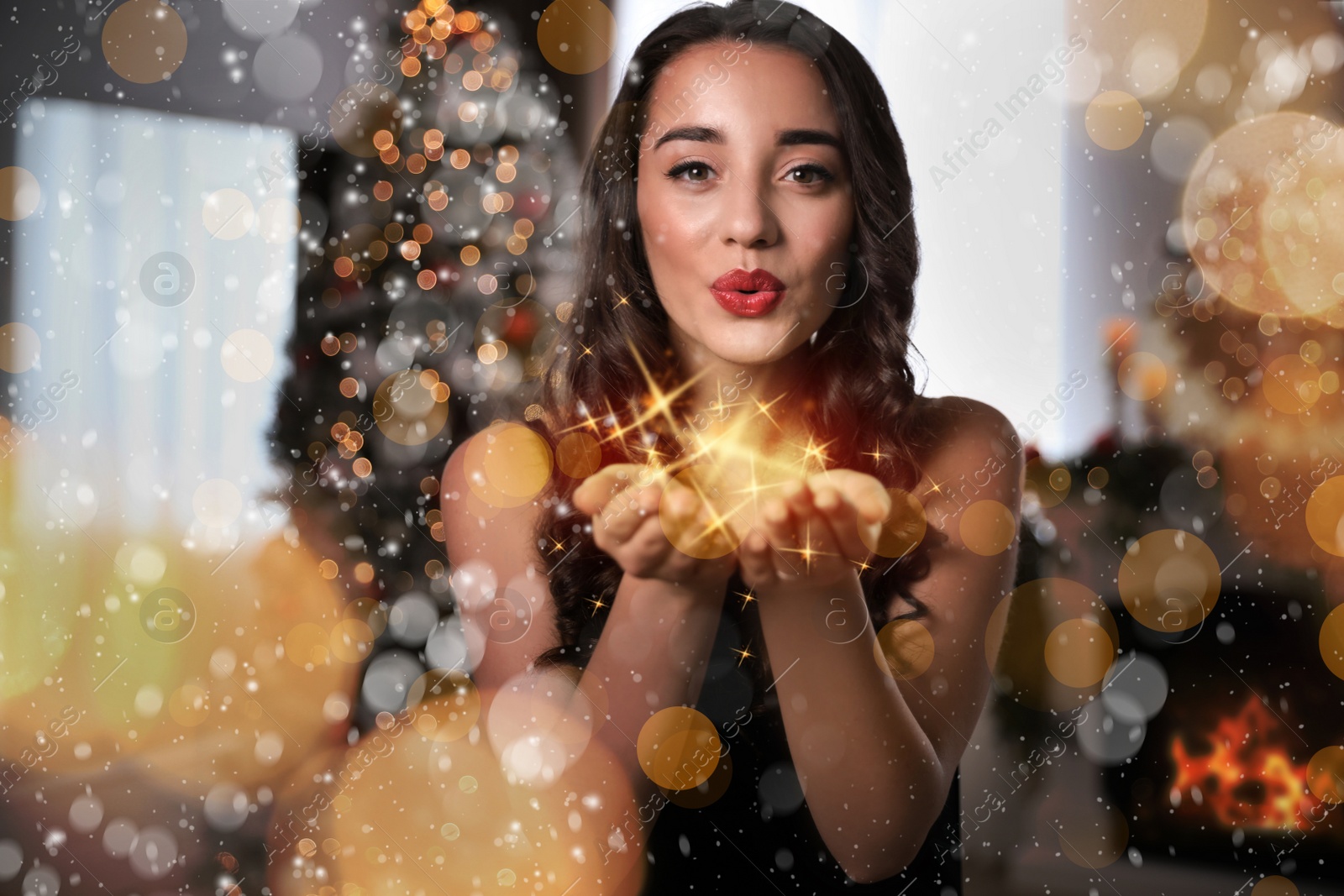 Image of Beautiful young woman wearing elegant dress blowing kiss in room decorated for Christmas