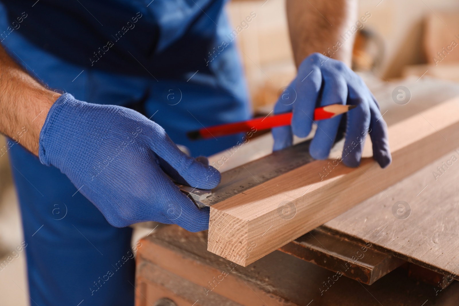 Photo of Professional carpenter making mark on wooden bar in workshop, closeup