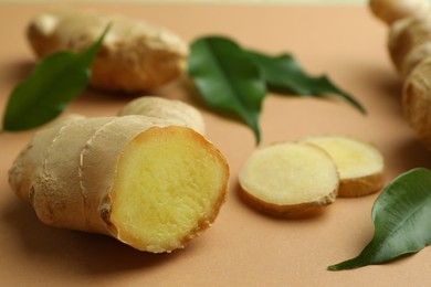 Photo of Fresh ginger and green leaves on light pale brown background, closeup
