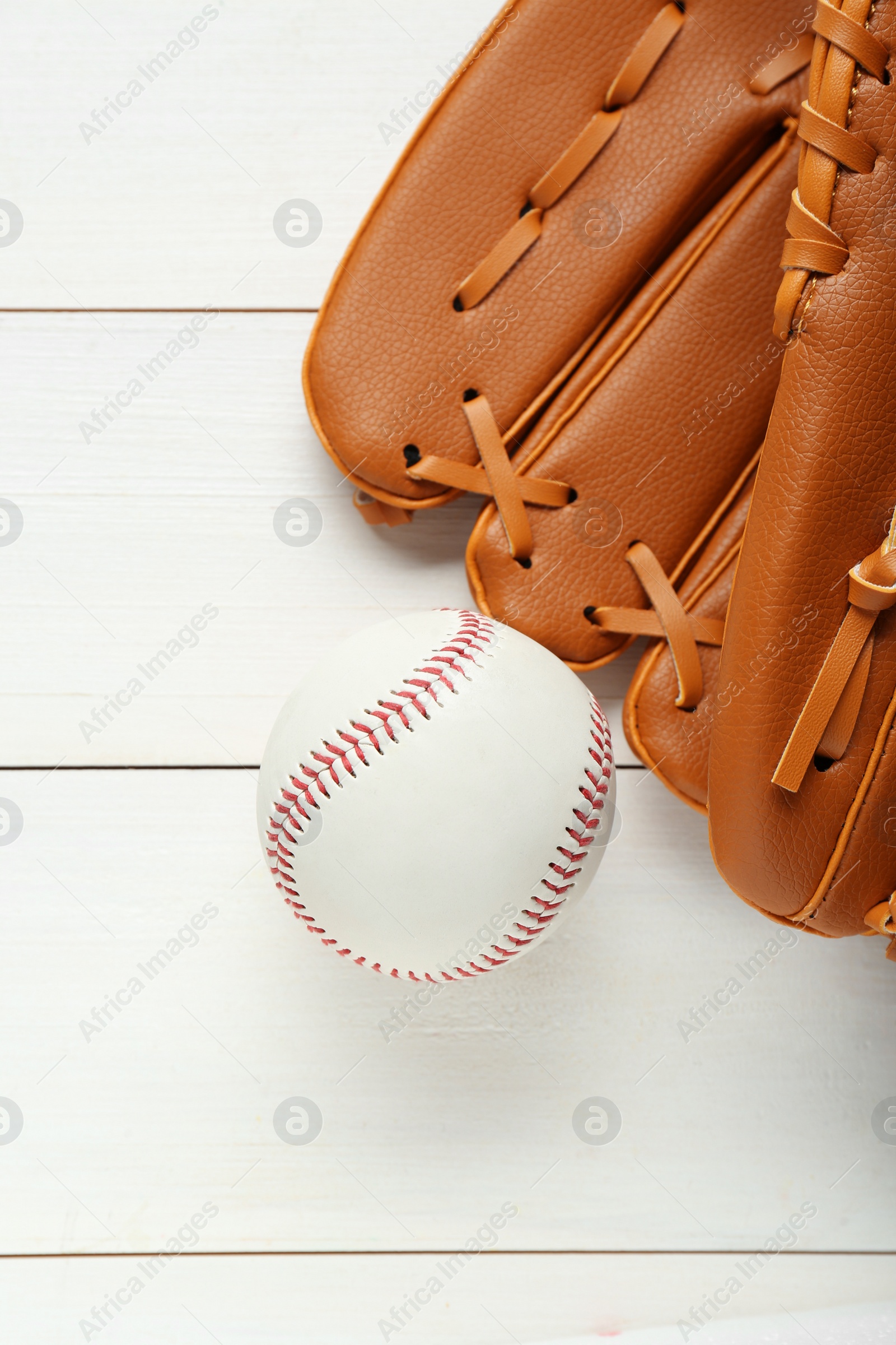 Photo of Catcher's mitt and baseball ball on white wooden table, top view. Sports game