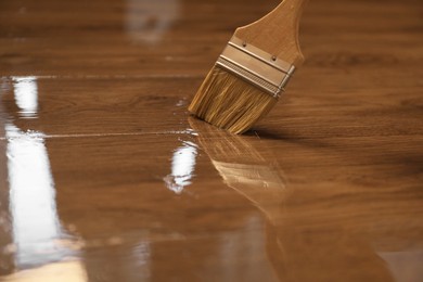 Photo of Varnishing wooden surface with brush, closeup view