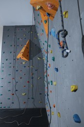 Wall with holds and climbing ropes in gym