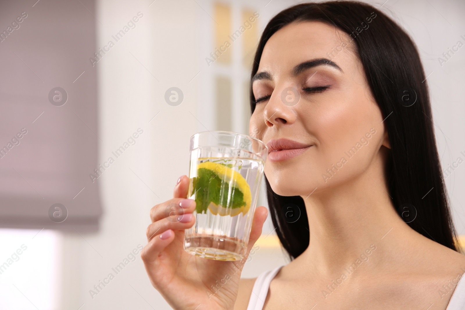 Photo of Young woman with glass of fresh lemonade at home