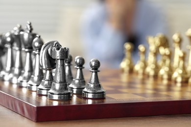 Chess board with silver pieces on wooden table, selective focus. Space for text