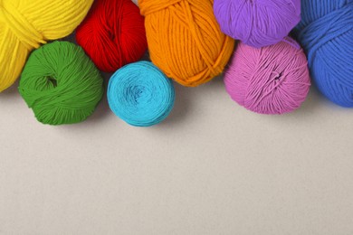 Image of Balls of yarn in rainbow colors on light background, flat lay. Space for text