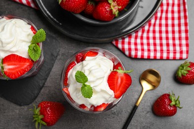 Photo of Delicious strawberries with whipped cream served on grey table, flat lay