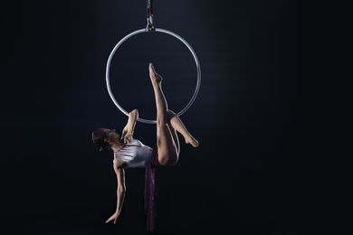 Photo of Young woman performing acrobatic element on aerial ring indoors