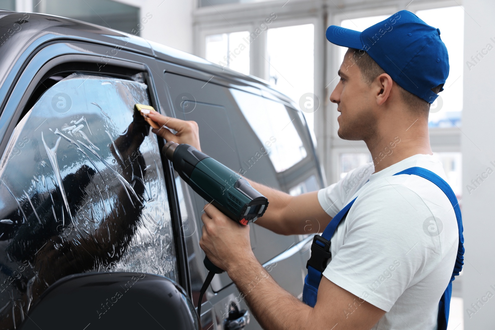 Photo of Worker tinting car window with foil in workshop