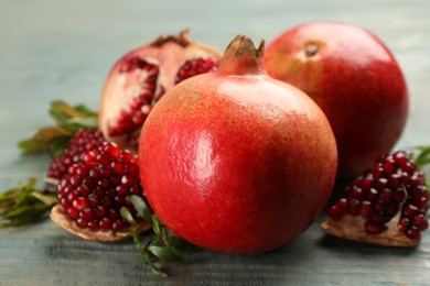 Delicious ripe pomegranates on blue wooden table, closeup