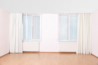 Photo of Windows with elegant curtains and blinds in empty room