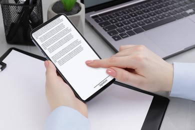 Image of Electronic signature. Woman using mobile phone at table, closeup