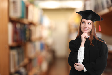 Image of Happy student wearing graduation hat in library, space for text