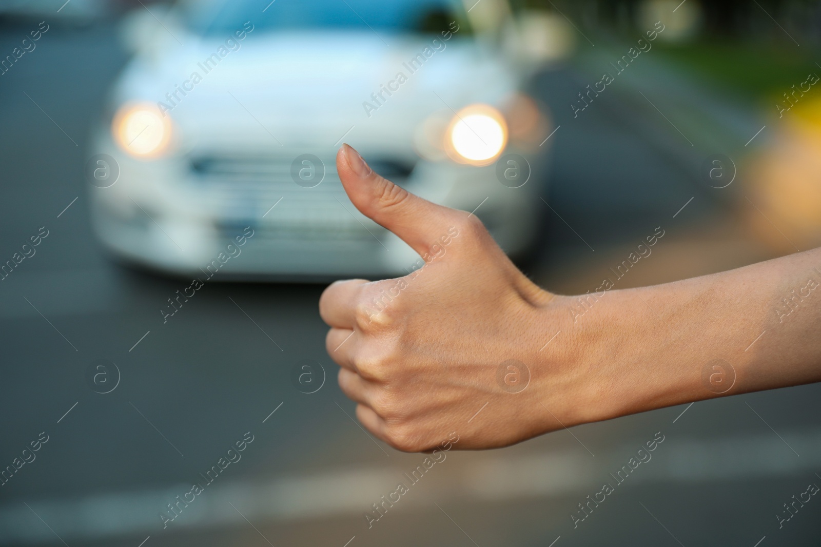 Photo of Woman hitchhiking taxi on city street, closeup