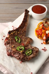 Delicious fried beef meat served with vegetables and sauce on wooden table